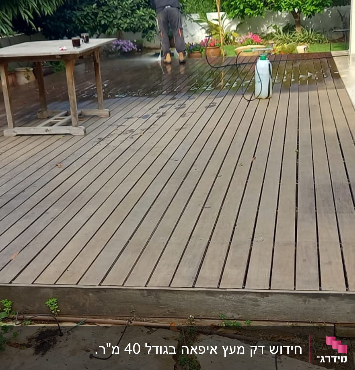 דק עץ עם שולחן, כיסאות ואדם מנקה עם צינור מים